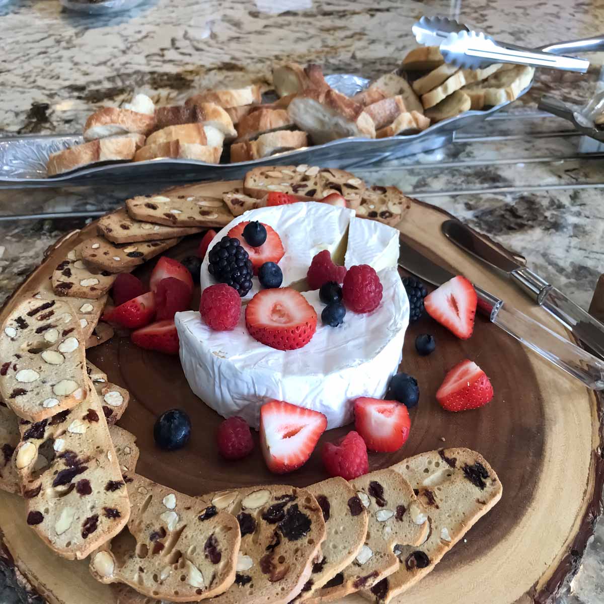 A Brie round circled by raisin and nut crisps and sprinkled with Raspberry, blueberry, blackberry and strawberry.