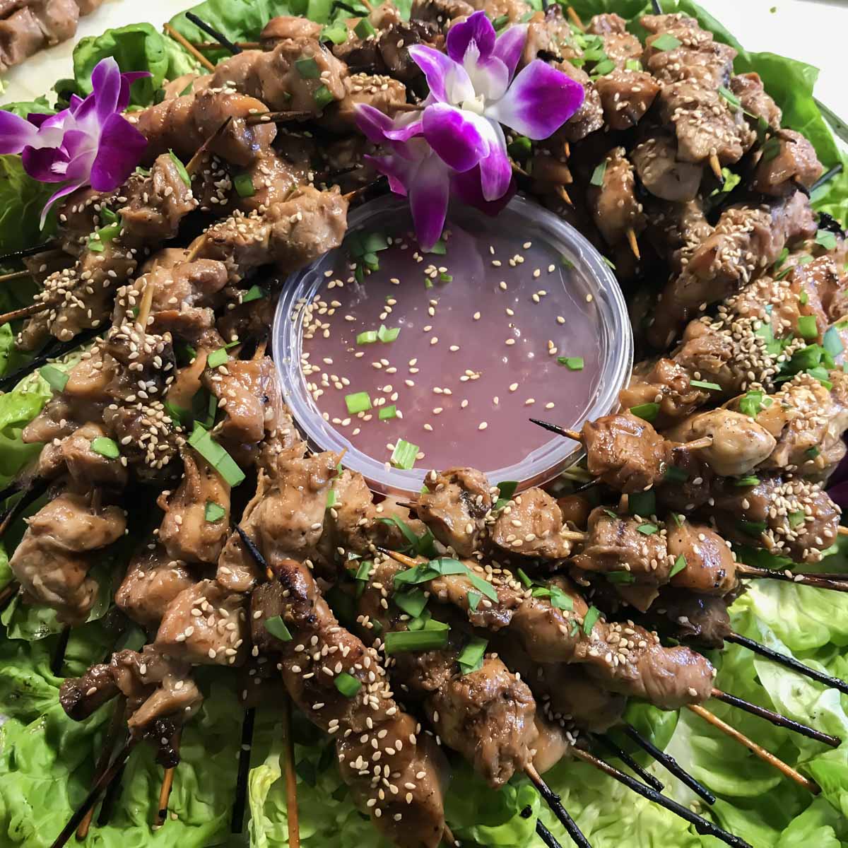 Sesame chicken kabobs, skewered and laid like a wreath on a floor of butter lettuce.