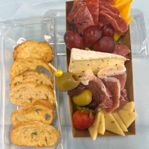 individual charcuterie with three meats, three cheeses, grapes, strawberry,green and kalamata olives and garlic toast